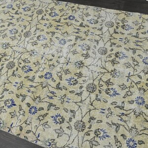 May include: A vintage rug with a cream background and a floral pattern in shades of blue and gray.