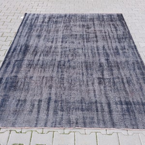 Puede incluir: Una alfombra azul oscuro con un aspecto desgastado y desteñido. La alfombra tiene un patrón sutil de líneas y remolinos.