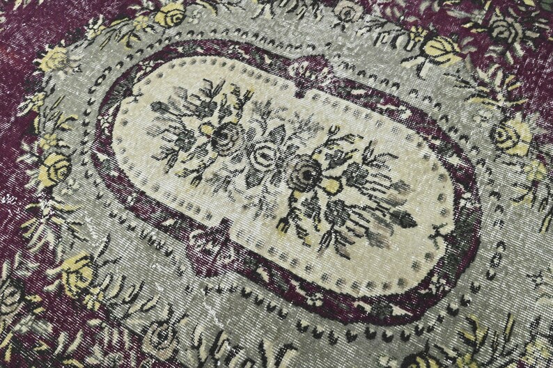 May include: A vintage rug with a floral pattern in shades of purple, gray, and yellow. The rug has a central oval medallion with a floral design.