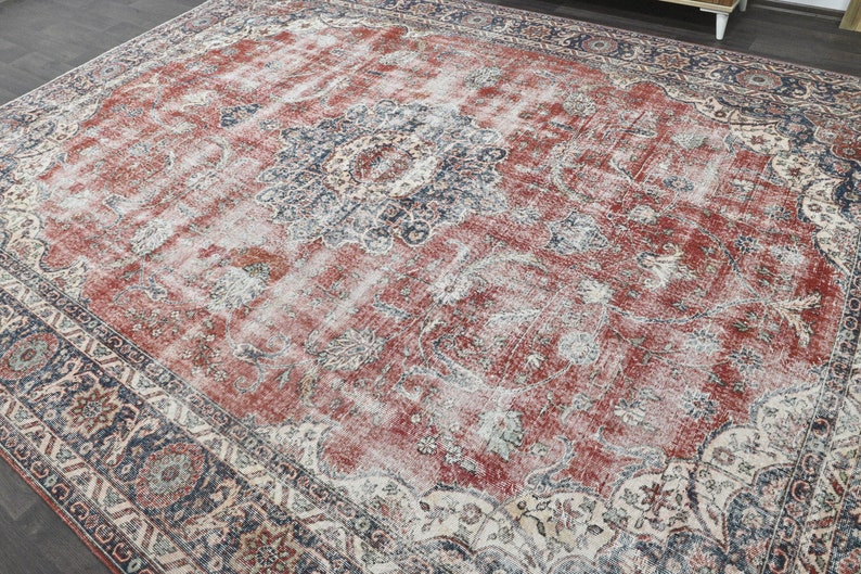 Pode incluir: Um tapete de estilo vintage com fundo vermelho e padr&otilde;es florais intrincados em tons de azul, creme e bege. O tapete tem um visual desgastado, o que lhe confere um toque &uacute;nico e antigo.