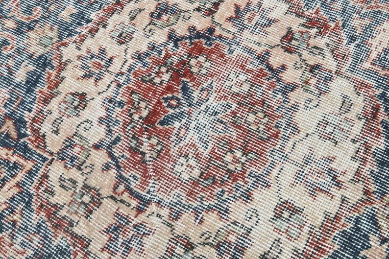 Pode incluir: Close-up de um tapete vintage com um padr&atilde;o detalhado em tons de azul, vermelho e creme.