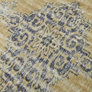 May include: A vintage-style rug with a faded, distressed look. The rug features a geometric pattern in shades of blue and beige.