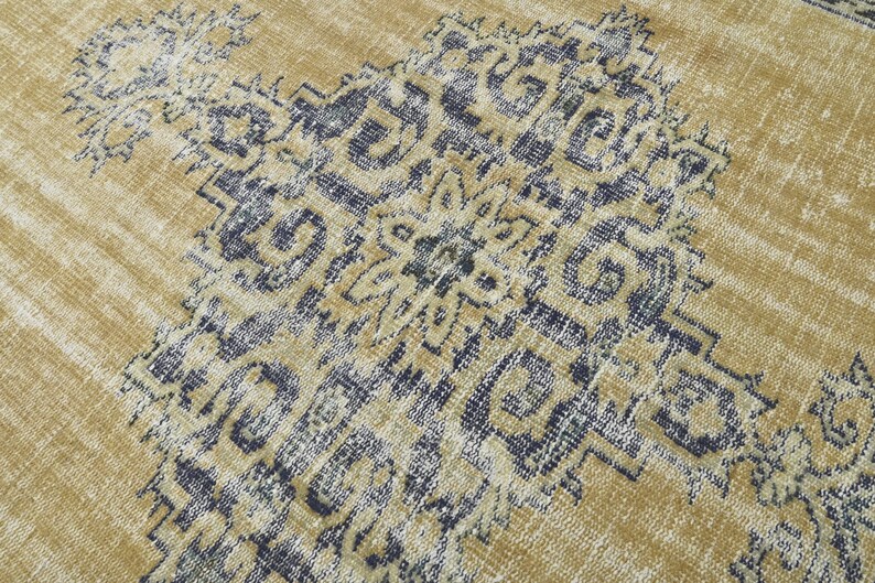 May include: A vintage-style rug with a faded, distressed look. The rug features a geometric pattern in shades of blue and beige.