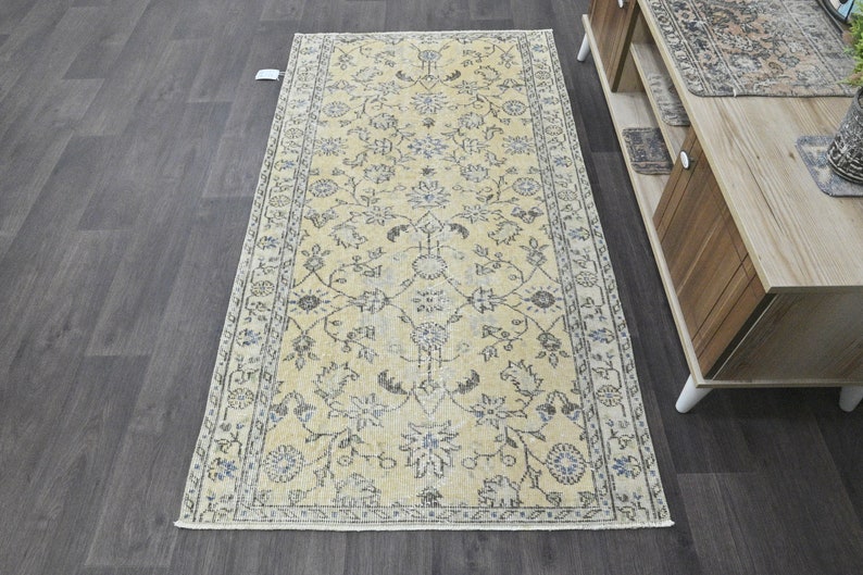 May include: A vintage style rug with a cream background and a floral pattern in shades of blue and gray. The rug has a fringed edge and is perfect for adding a touch of traditional elegance to any room.