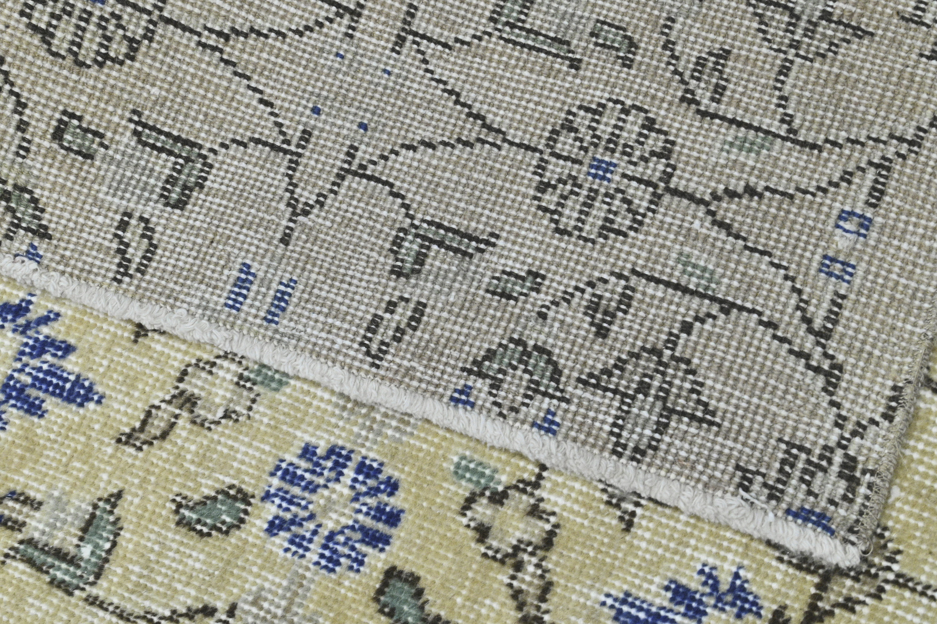 May include: Close-up of a beige and cream patterned rug with blue and green accents. The rug has a fringe border.