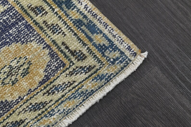 May include: Close-up of a woven rug with a fringe edge. The rug has a geometric pattern in shades of blue, yellow, and white.