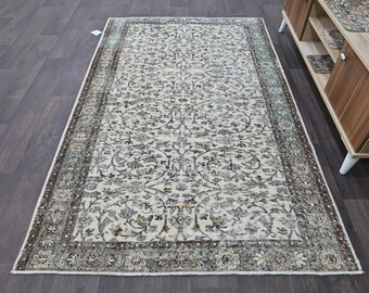 May include: A vintage-style rug with a floral pattern in shades of brown, beige, and teal. The rug has a distressed look and a fringed edge.