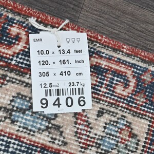 Pode incluir: Uma etiqueta branca com texto preto e um c&oacute;digo de barras. A etiqueta lista as dimens&otilde;es de um tapete em p&eacute;s, polegadas e cent&iacute;metros. O tapete mede 10 p&eacute;s por 13,4 p&eacute;s, 120 polegadas por 161 polegadas e 305 cent&iacute;metros por 410 cent&iacute;metros. A etiqueta tamb&eacute;m lista a &aacute;rea do tapete como 12,5 metros quadrados e seu peso como 23,7 quilogramas. O n&uacute;mero do c&oacute;digo de barras &eacute; 9406.