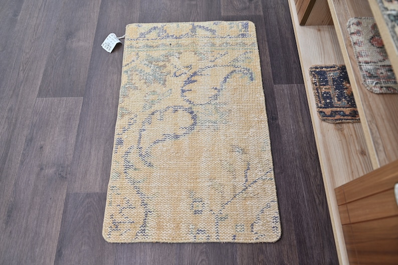 K&ouml;nnte beinhalten: Ein hellgelber und blauer Teppich mit einem floralen Muster. Der Teppich ist aus einem weichen, gewebten Material gefertigt und hat einen Fransenrand.