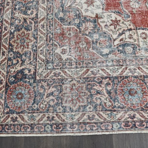 Pode incluir: Um tapete vintage com um padr&atilde;o floral desbotado em vermelho, azul e branco. O tapete tem um aspecto desgastado e uma borda franjada.