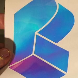 May include: A holographic sticker with a blue, purple, and white geometric design. The sticker is shaped like a heart.