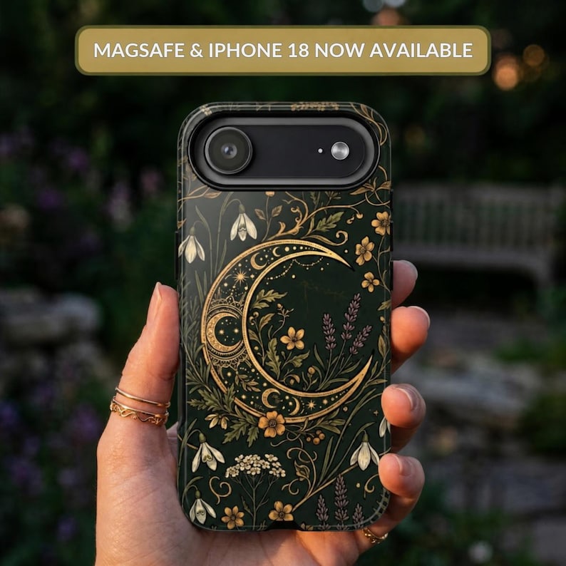 May include: A dark green phone case featuring a gold crescent moon design surrounded by intricate floral and botanical illustrations. The text MAGSAFE & IPHONE 18 NOW AVAILABLE is displayed at the top of the image above the phone case.