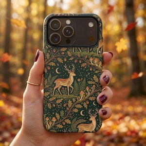 May include: A forest-themed phone case featuring a deer, mushrooms, and foliage in shades of green, brown, and gold. The case has a dark green background with a repeating pattern of woodland elements. The design includes a crescent moon and acorns.