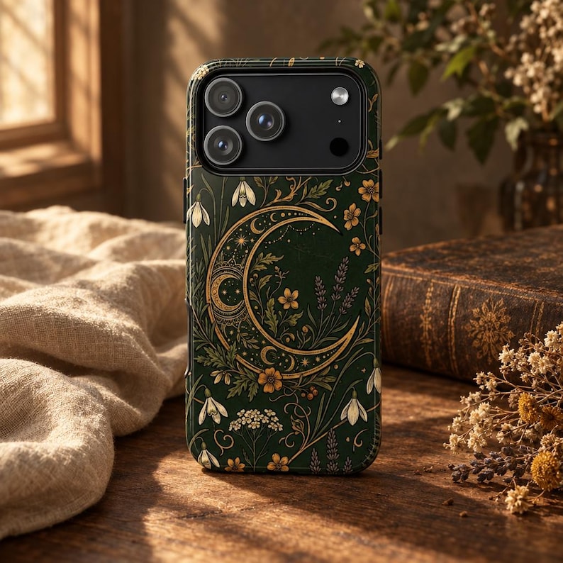 K&ouml;nnte beinhalten: Eine dunkelgr&uuml;ne Smartphone-H&uuml;lle mit einer goldenen Mondsichel-Illustration, umgeben von komplizierten botanischen Mustern, darunter kleine wei&szlig;e Blumen, bl&auml;ttrige Ranken und Lavendelzweige, mit einem Ausschnitt f&uuml;r die Dreifachkamera.