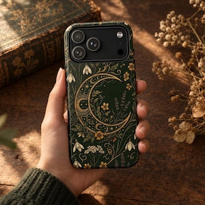 K&ouml;nnte beinhalten: Eine dunkelgr&uuml;ne Smartphone-H&uuml;lle mit einer goldenen Mondsichel-Illustration, umgeben von komplizierten botanischen Mustern, darunter kleine wei&szlig;e Bl&uuml;ten, gelbe Blumen und bl&auml;ttrige Ranken, mit einem schwarzen Ausschnitt f&uuml;r die Kameralinse.
