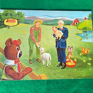 May include: A vintage Captain Kangaroo jigsaw puzzle featuring a brown bear, a farmer, a man holding a piglet, a lamb, a rabbit, and a chicken. The puzzle is set in a farm scene with a red barn and a pond.