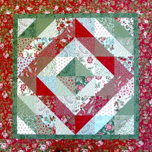 May include: A quilt with a patchwork design featuring red, green, and white fabric. The quilt is made up of triangles and squares, and the fabric has a variety of patterns, including floral, paisley, and geometric.