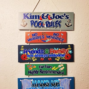 Puede incluir: Un letrero de pared colgante con cinco paneles rectangulares con gráficos de temática de piscina. El texto incluye Kim & Joe's POOL RULES, NO HURRIES NO WORRIES, Friends & Family are always welcome, Flip Flops Highly Recommended y HANG UP YOUR TOWEL.