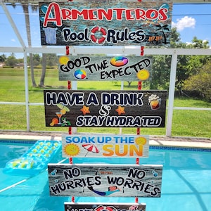 May include: A hanging vertical sign set with six rectangular wooden planks connected by red ropes. The signs feature text including Armenteros Pool Rules, Good Time Expected, Have a Drink & Stay Hydrated, Soak Up The Sun, No Hurries No Worries, and Make Memories, decorated with colorful illustrations of suns, drinks, and pool floats.