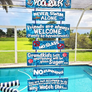 Puede incluir: Un letrero colgante vertical con un fondo de agua azul que presenta el texto MEMA & PAPA'S POOL RULES, NEVER SWIM ALONE, Friends are always WELCOME, NO GLASS, Grandkids left unattended will be given Sugar, NO RUNNING, Hey Watch this, y más.