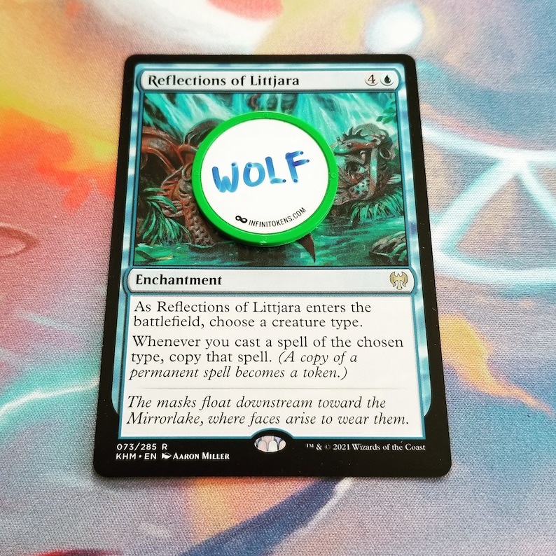 May include: A Magic: The Gathering card named "Reflections of Littjara" with a green and white circular token that says "WOLF". The card features a blue and green illustration and text detailing its gameplay effects.
