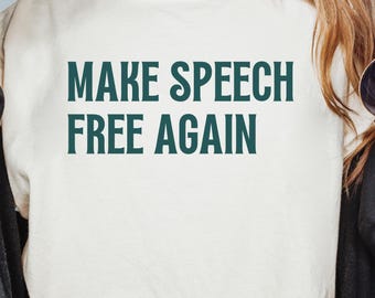 Puede incluir: Sudadera color crema con el texto "MAKE SPEECH FREE AGAIN" en letras verde oscuro. La sudadera se lleva con una chaqueta negra y gafas de sol.