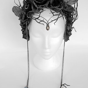 May include: A black floral crown with black roses and branches, accented with dangling chains and crystal drops.