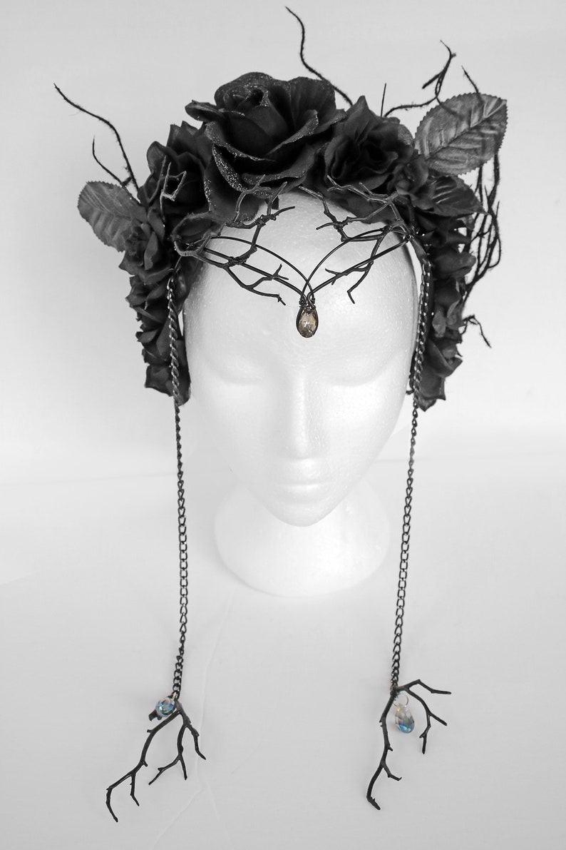 May include: A black floral crown with black roses and branches, accented with dangling chains and crystal drops.
