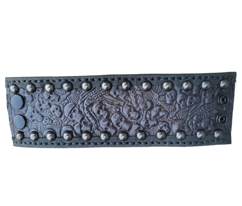 May include: A black leather bracelet with a skull pattern and silver studs.