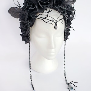 May include: Black floral crown with black roses and branches, accented with dangling chains and blue crystal beads.
