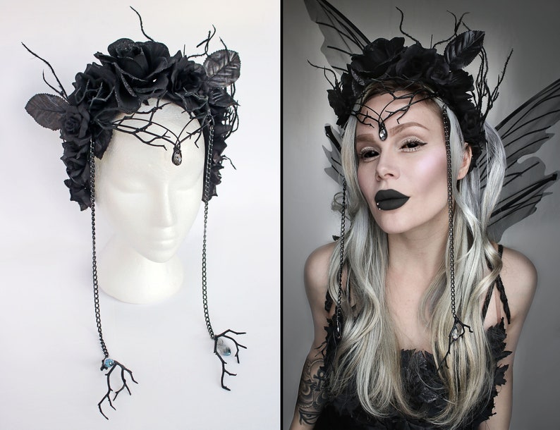 May include: Black floral crown with black roses, leaves, and branches. The crown has two dangling chains with black branches and blue crystals at the ends.