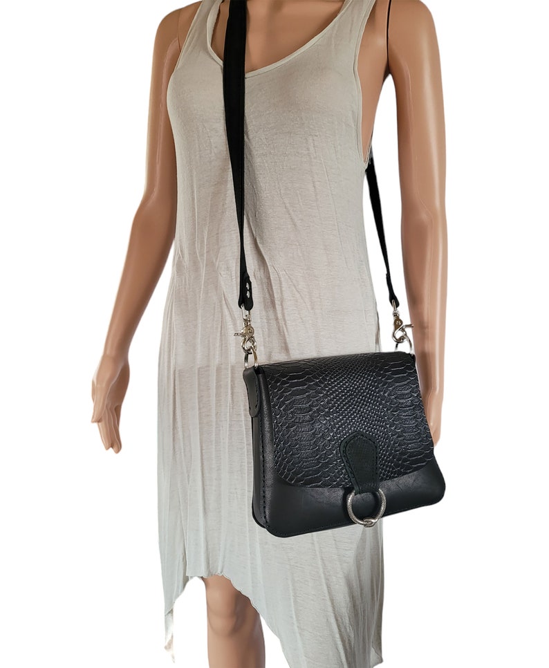 May include: A black leather crossbody bag with a snakeskin pattern and a silver ring detail.