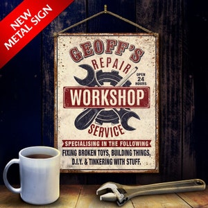 May include: A rusty metal sign with the text "Geoff's Repair Workshop Service" in red and black lettering. The sign also includes a gear and wrench design and the text "Specialising in the following: Fixing broken toys, building things, D.I.Y. & tinkering with stuff."