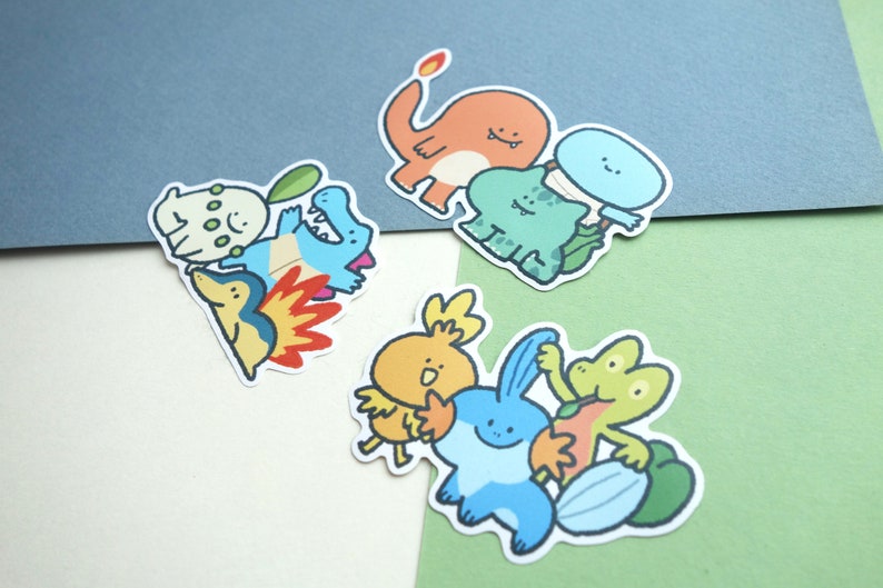 May include: A set of colourful cartoon character stickers featuring various Pokemon characters, including Charmander, Bulbasaur, Squirtle, and others. The stickers are printed on white paper and have a glossy finish.