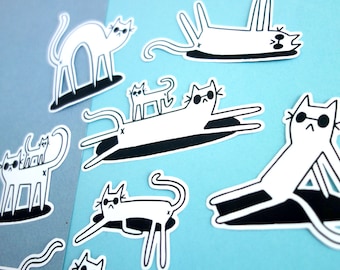May include: A set of nine black and white cat stickers on a blue background. The cats are in various poses, including sitting, lying down, and standing. Some of the cats are wearing sunglasses.