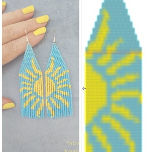 May include: A pair of long, beaded earrings with a sun design. The earrings are blue with yellow accents. The earrings are shown in a close-up image with a hand holding them.