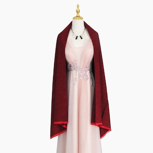 May include: A burgundy shawl with a red trim draped over a pink dress with silver embellishments.