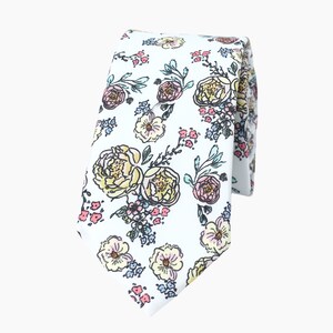 May include: A white tie with a floral pattern featuring yellow, pink, and blue flowers. The flowers are outlined in black and have a hand-drawn style.