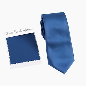 Peut inclure: Une cravate en satin bleu avec un échantillon de tissu étiqueté "Dress Swatch Reference" en texte blanc.