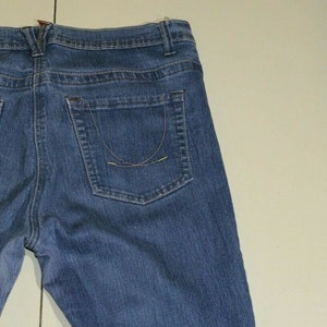 Puede incluir: Un par de pantalones vaqueros azules con un bolsillo trasero. El bolsillo tiene un detalle de costura curvado.