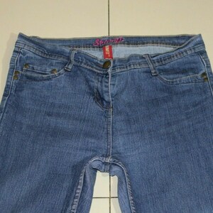 Puede incluir: Un par de pantalones vaqueros azules con una etiqueta rosa "Spring" en la cintura.