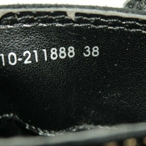 Pode incluir: Close-up do interior de um sapato preto com texto branco que diz "10-211888 38".