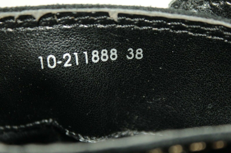 Pode incluir: Close-up do interior de um sapato preto com texto branco que diz "10-211888 38".