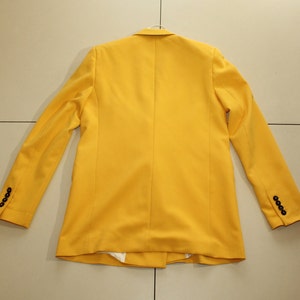 Puede incluir: Una chaqueta amarilla brillante con botones negros en las mangas.