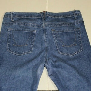 Puede incluir: Un par de pantalones vaqueros azules de mezclilla con un estilo cl&aacute;sico de cinco bolsillos. Los pantalones tienen una pierna recta y una cintura de altura media.