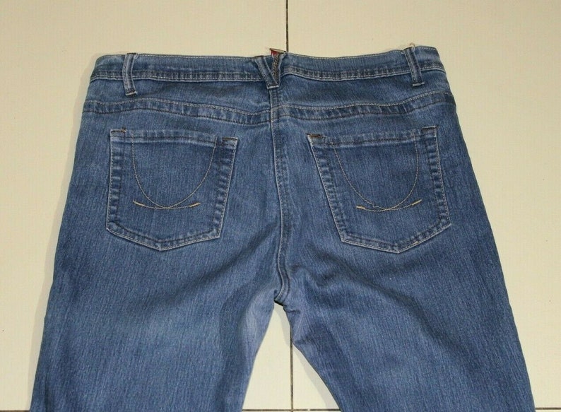 Puede incluir: Un par de pantalones vaqueros azules de mezclilla con un estilo cl&aacute;sico de cinco bolsillos. Los pantalones tienen una pierna recta y una cintura de altura media.