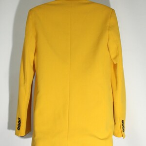 Puede incluir: Una chaqueta amarilla brillante con cierre de un solo bot&oacute;n y mangas largas. La chaqueta tiene un corte cl&aacute;sico y est&aacute; hecha de una tela suave y ligera.