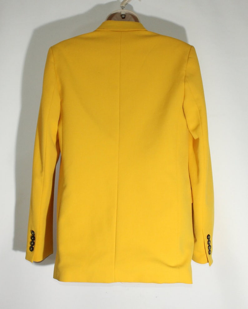 Puede incluir: Una chaqueta amarilla brillante con cierre de un solo bot&oacute;n y mangas largas. La chaqueta tiene un corte cl&aacute;sico y est&aacute; hecha de una tela suave y ligera.