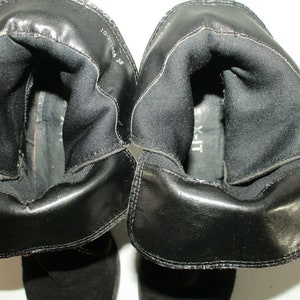 Pode incluir: Close-up do interior de um par de botas de camur&ccedil;a pretas. As botas t&ecirc;m um forro preto e o tamanho 10,5 est&aacute; escrito no interior de uma bota.