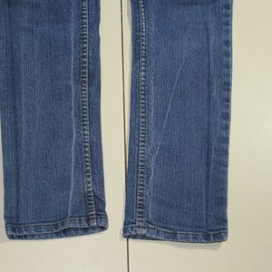 Puede incluir: Un par de pantalones vaqueros azules de denim con corte recto. Los vaqueros tienen un lavado oscuro y est&aacute;n hechos de una tela suave y c&oacute;moda.